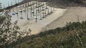 Une plage avec des bateaux et une colline rocheuse.