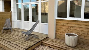 Une terrasse en bois avec une chaise et une poubelle.