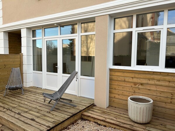 A wooden deck with a chair and a trash can.