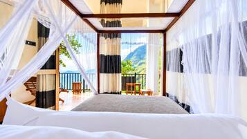 A bedroom with a bed, a balcony, and a view of mountains.