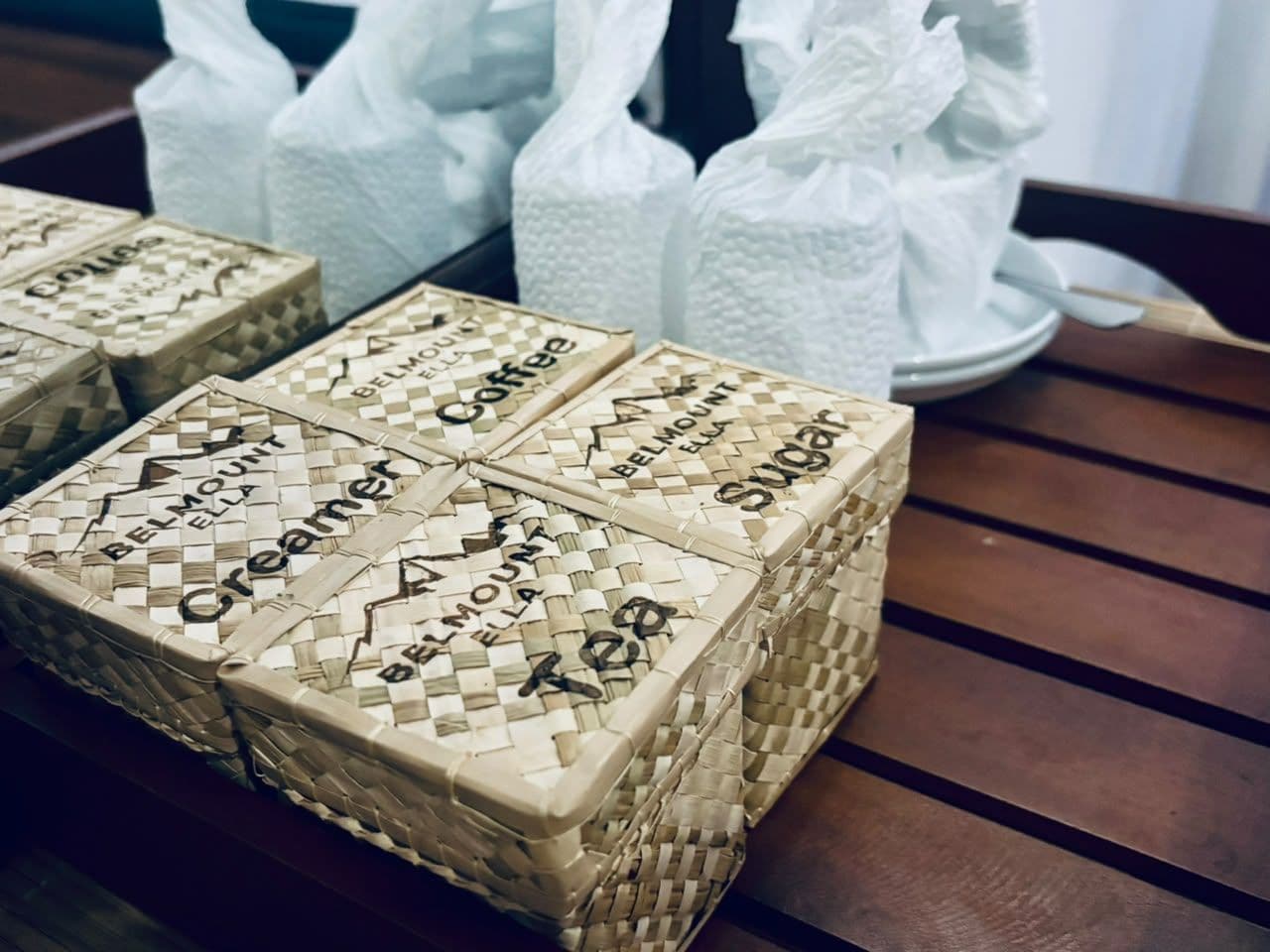 Une table en bois sur laquelle reposent quatre paniers en osier, chacun étant étiqueté avec le nom d’un thé différent.