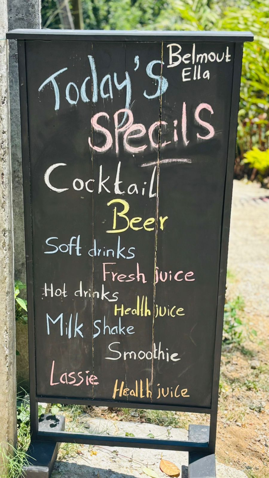 A blackboard menu listing today's specials including cocktail, beer, soft drinks, fresh juice, milk shake, smoothie, and lassi.