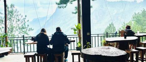 Une terrasse dotée de tables et de chaises en bois, offrant une vue sur un paysage montagneux.