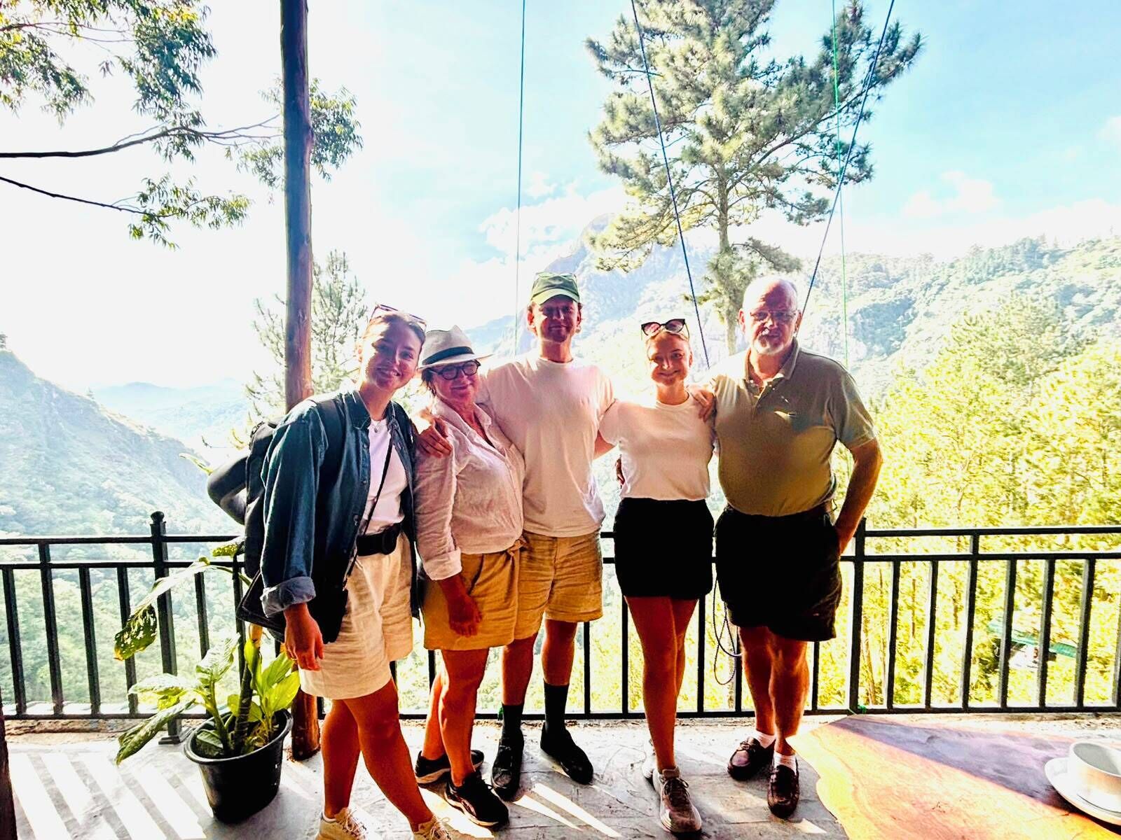 A group of people standing on a balcony with a view of a mountainous landscape.