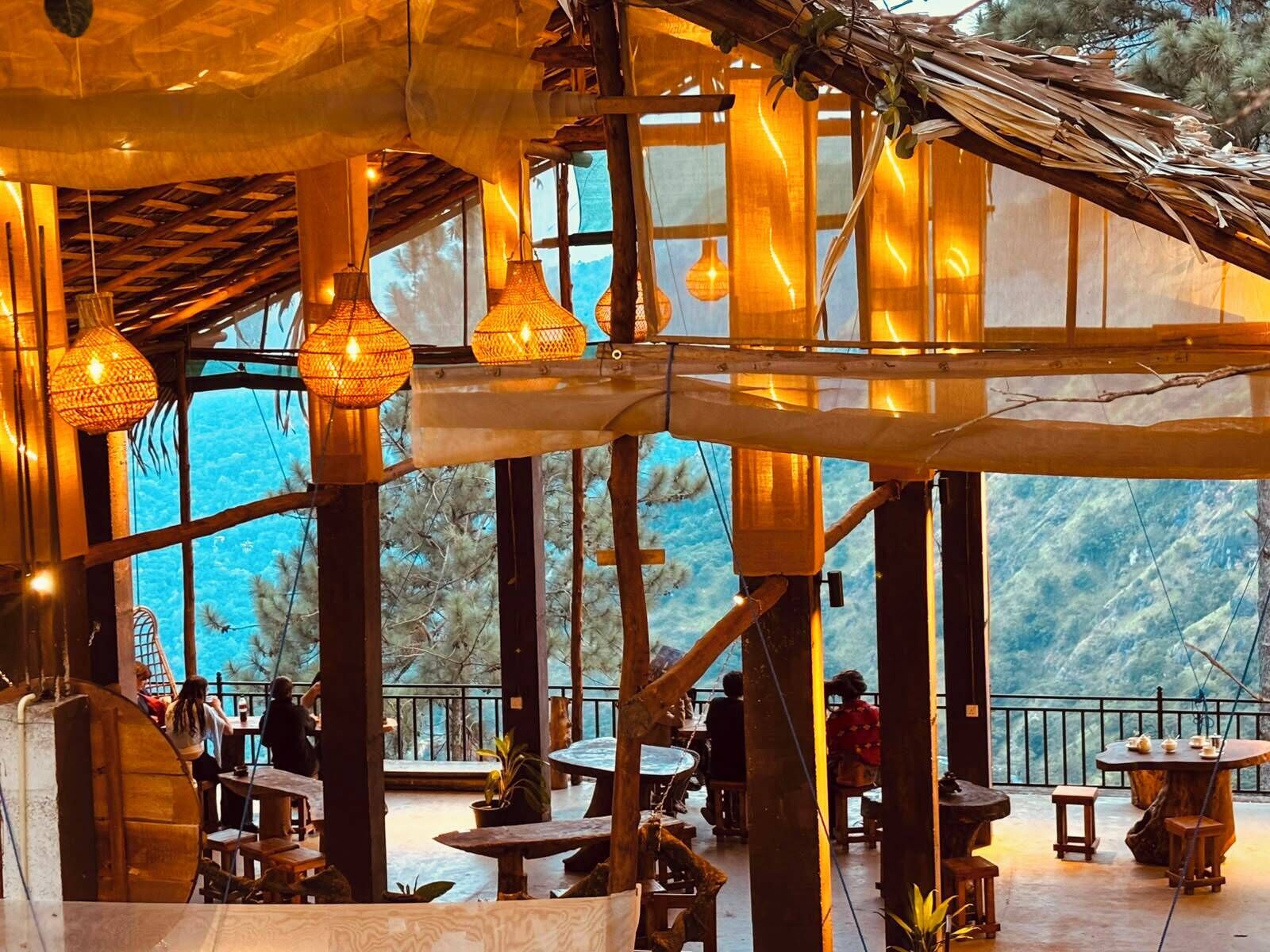 Un intérieur agrémenté de poutres en bois, de luminaires suspendus et de tables avec des chaises.