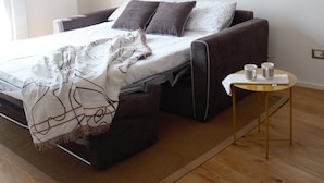 Une chambre moderne avec un lit, une petite table avec des tasses et un plancher en bois.