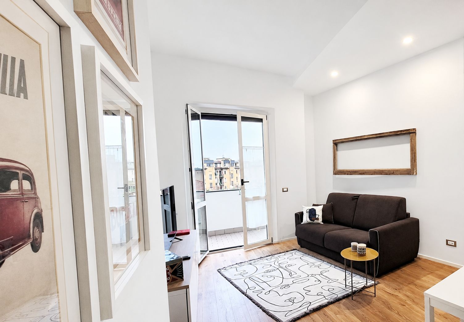 A modern living room with a sofa, a small side table, a rug, and a framed picture on the wall.