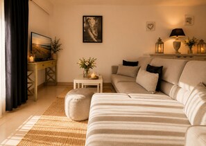 A living room with a sofa, ottoman, and a small table with candles and flowers. - Le Aix Rotonde Mirabeau 4* - T4 / 110 m2 downtown with terrace 30 m2 garage (Aix-en-Provence)
