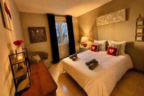 A hotel room with a bed, a bedside table, a lamp, a chair, and a window with curtains. - Le Aix Rotonde Mirabeau 4* - 4-room apartment / 110 m² in the city center with a 30 m² terrace and a garage (Aix-en-Provence)