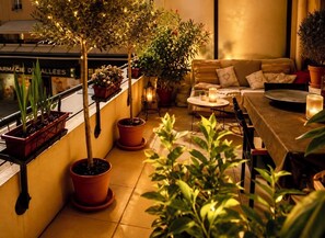 A cozy outdoor seating area with potted plants, a table with candles, and a sofa. - Le Aix Rotonde Mirabeau 4* - 4-room apartment / 110 m² in the city center with a 30 m² terrace and a garage (Aix-en-Provence)