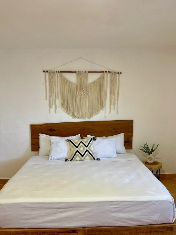 A neatly made bed with white linens and a wooden headboard.