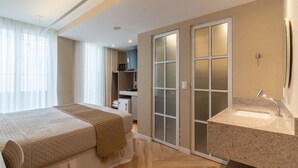 A modern hotel room with a bed, a bathroom with a sink, and a sliding glass door leading to a kitchenette. - Refuge a Few Steps From Copacabana Beach Q8 (Rio de Janeiro)