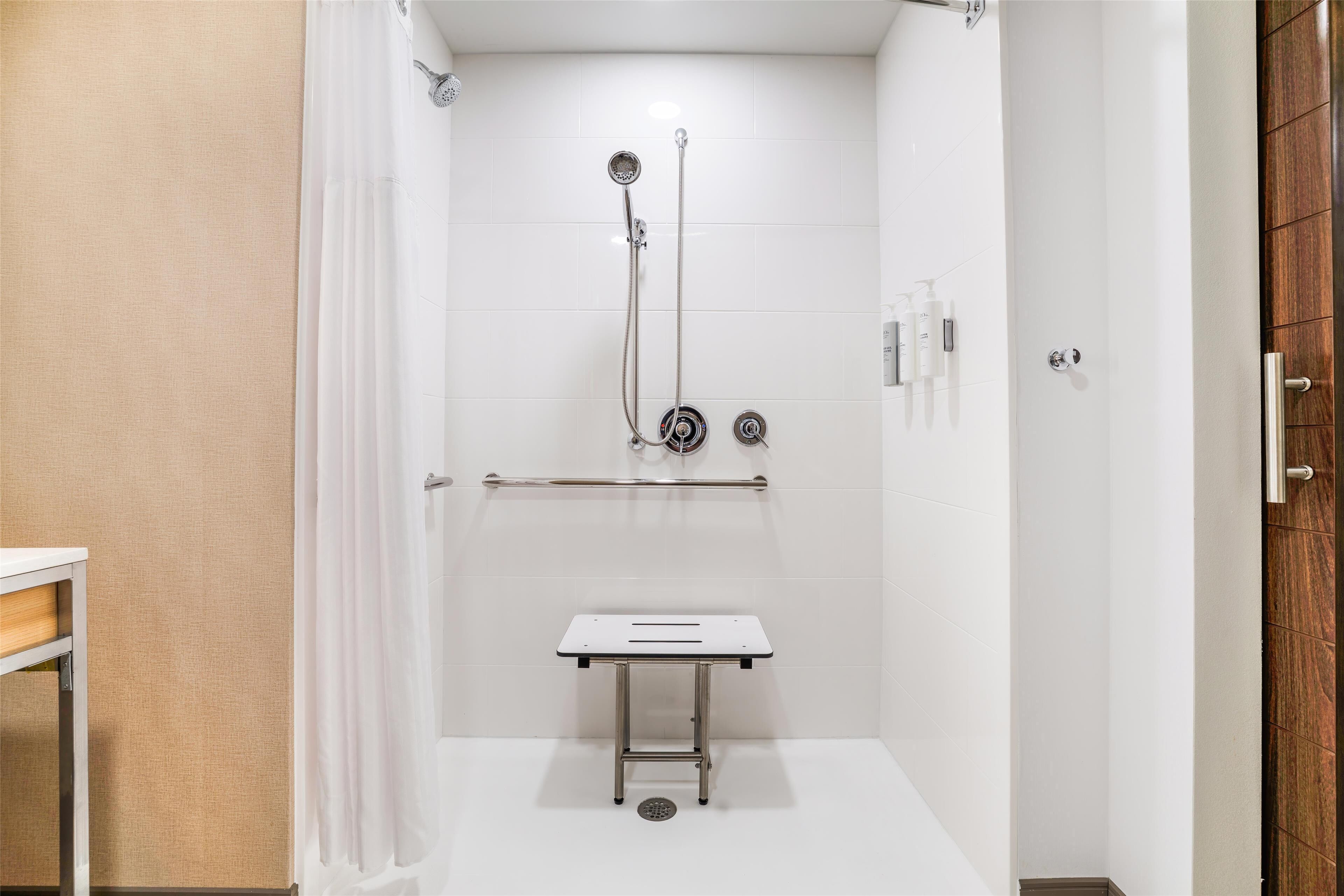 Un baño moderno con ducha, una mesita y un perchero.
