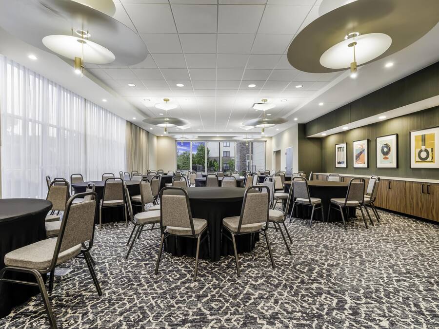 A conference room with round tables and chairs, large windows, and framed artwork on the walls.