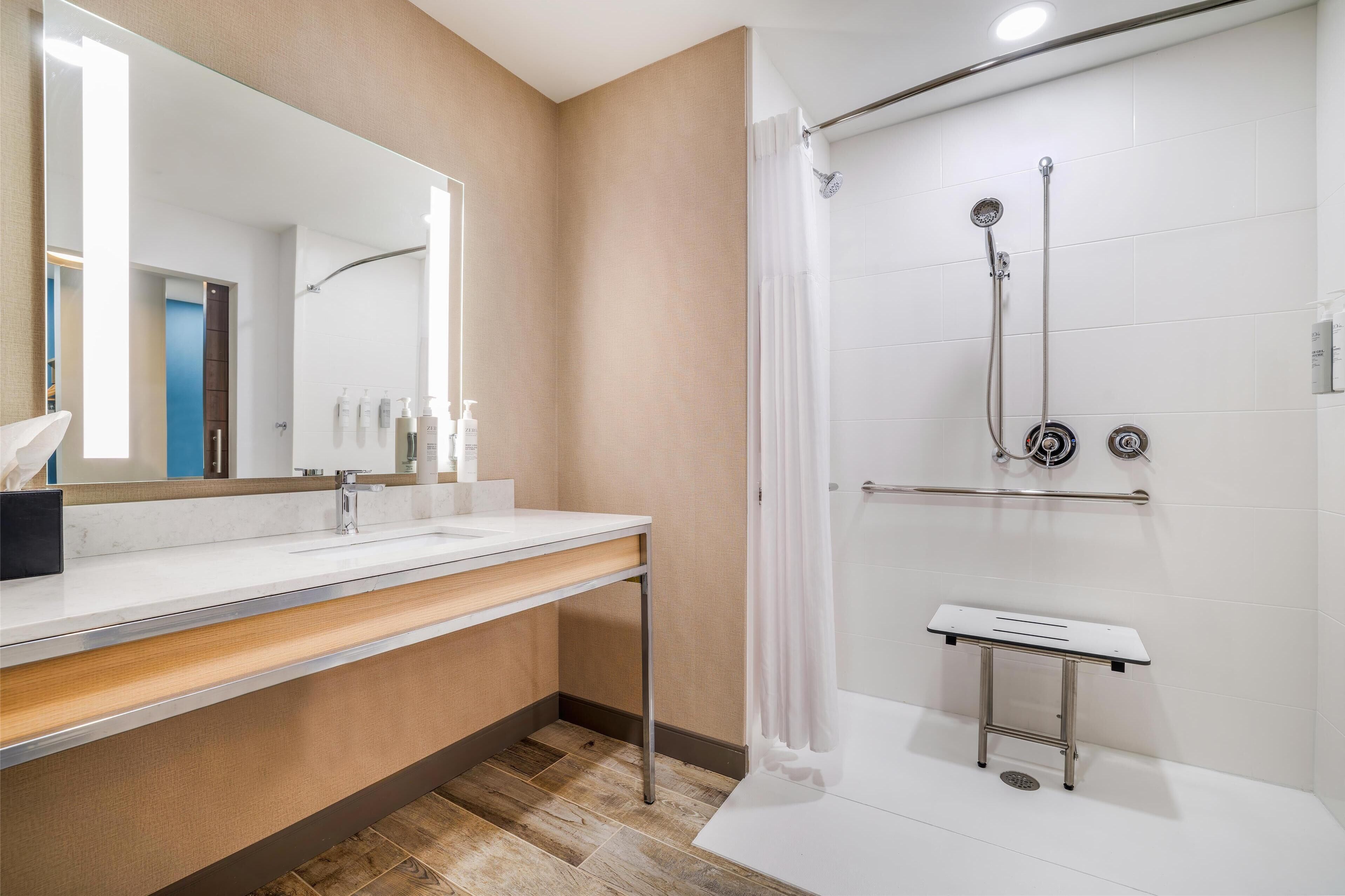 Un baño moderno con un espejo grande, un lavabo y una zona de ducha.