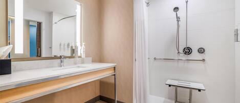 Un baño moderno con un espejo grande, un lavabo y una zona de ducha.