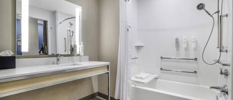 Un baño moderno con un espejo grande, un lavamanos, una ducha con cortina y una bañera.