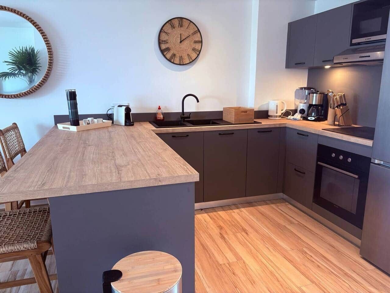 Een moderne keuken met een houten kookeiland, donkere kasten, een inbouwoven en een magnetron.