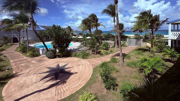 Resort com piscina, palmeiras e vista para o oceano.