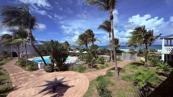 A resort with a pool, palm trees, and a view of the ocean.