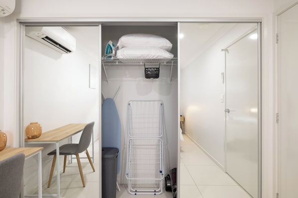 A compact room with a desk, chair, and a drying rack. - Smart Suites Self Check-in Apartments - 39A Freney (Rocklea)