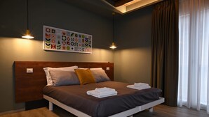 A modern bedroom with a wooden headboard, a large bed with brown bedding, two bedside lamps, and a wall art piece above the bed.