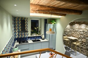 Una cocina moderna con un salpicadero de azulejos geométricos, una pared de piedra y un techo de madera rústica.