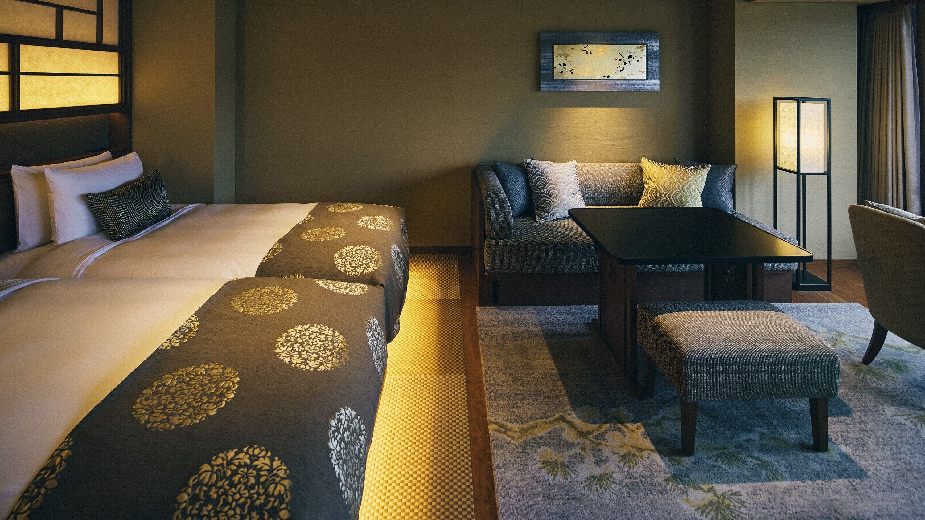 A hotel room with a bed, sofa, table, and chair.