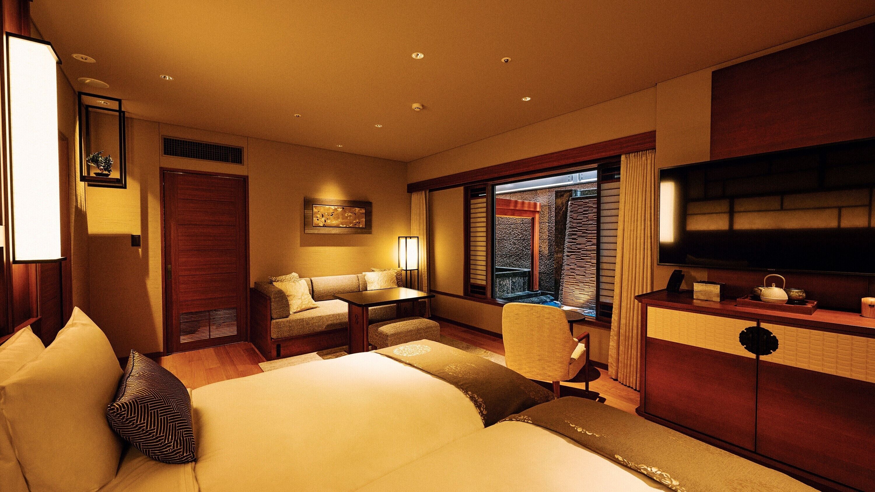 A hotel room with a bed, a desk, a chair, a TV, and a window with a view.