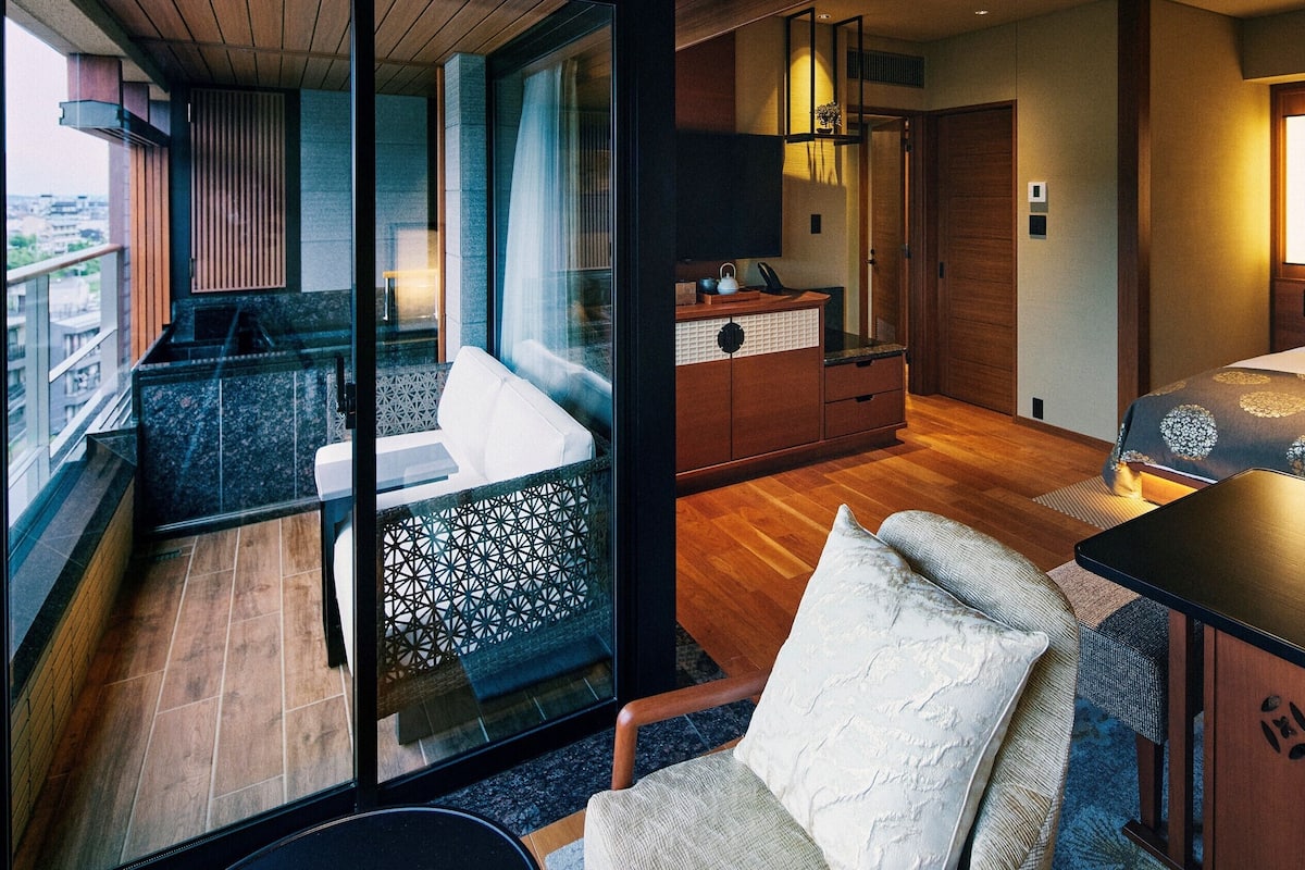 Ein modernes Hotelzimmer mit Balkon, einem Bett, einem Schreibtisch und einer Sitzecke.