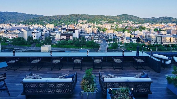 A rooftop terrace with outdoor seating and a view of a cityscape with buildings and hills in the background. - Sora Niwa Terrace Kyoto (Kyoto)