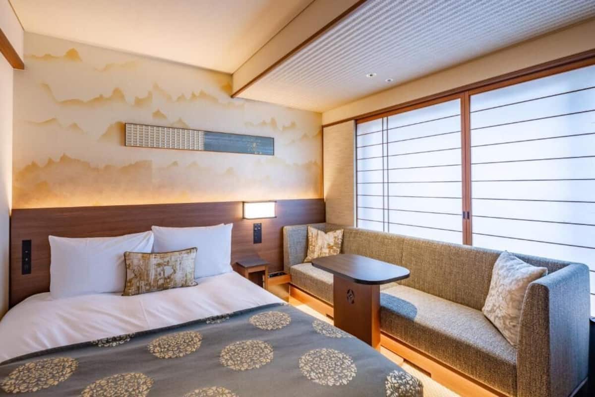 Ein Hotelzimmer mit Bett, Sofa und kleinem Tisch.