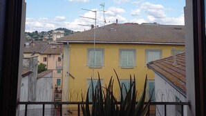 Ein gelbes Gebäude mit einem Ziegeldach und einem Balkon mit Metallgitter.