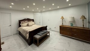 A bedroom with a bed, bench, dresser, and lamps. - Virginia poolside Oasis: your Woodland Escape (Chesterfield)