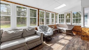 A sunroom with a sofa, a bean bag chair, and a dining table. - Virginia poolside Oasis: your Woodland Escape (Chesterfield)