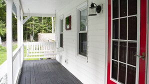 A covered porch with a white railing, a red door, and a window with a white frame. - Virginia poolside Oasis: your Woodland Escape (Chesterfield)