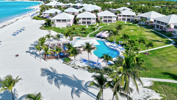 Un complexe hôtelier avec accès à la plage, une piscine et plusieurs bâtiments présentant un style architectural uniforme.