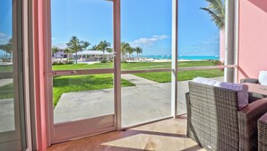 Un balcon avec vue sur la plage, des meubles d’extérieur et un ciel dégagé.