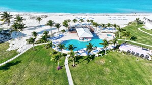 Vue aérienne d’un complexe hôtelier avec une piscine, une plage et l’océan.