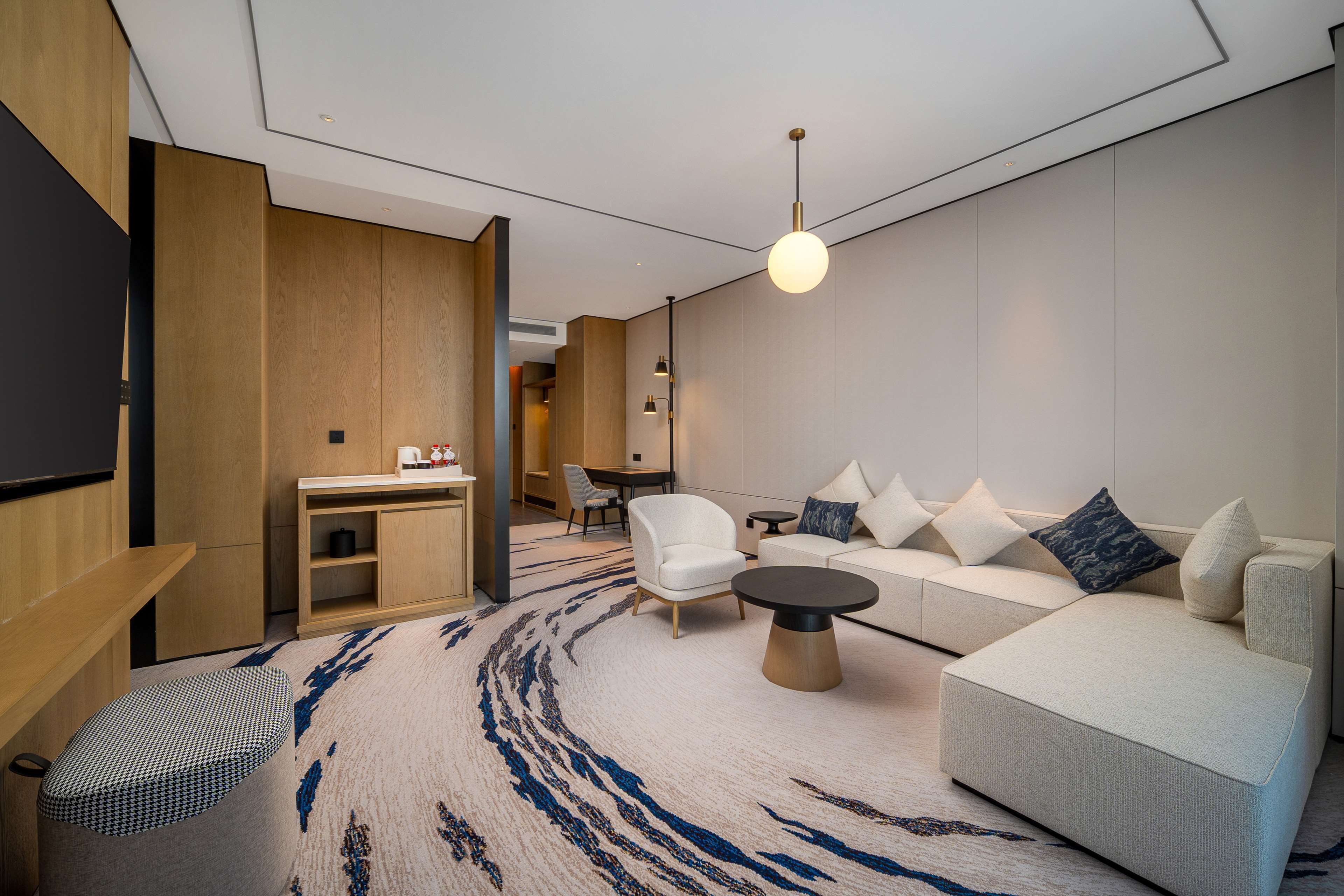 A modern living room with a sofa, armchairs, a coffee table, and a TV.