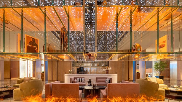 A modern hotel lobby with a glass atrium, a central seating area with sofas, a coffee bar, and a fire feature. - Hilton Garden Inn Ordos Kangbashi (Ordos)