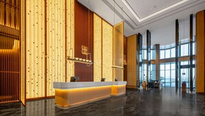A modern hotel lobby with a reception desk, large windows, and a decorative wall with vertical panels. - Hilton Garden Inn Ordos Kangbashi (Ordos)