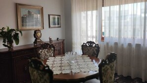 Una sala da pranzo con un tavolo di legno, sedie, un orologio e due quadri appesi al muro.
