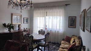 Zona pranzo con un lampadario, un tavolo, sedie e un divano.