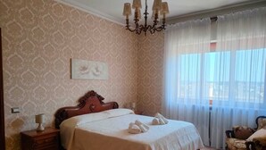 Una camera da letto con un letto grande, un lampadario, un comodino e una sedia.