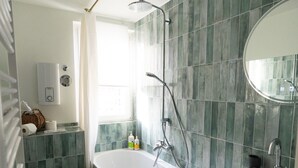 Ein Badezimmer mit freistehender Badewanne, Waschbecken, Toilette und Fenster.