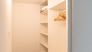 Ein begehbarer Kleiderschrank mit offenen Regalen und einer Kleiderstange, mit einem gemusterten Teppichboden.