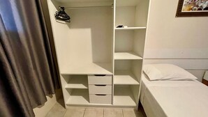 A room with a bed, a wardrobe with multiple shelves and drawers, and a hanging rack. - AP 31 Ala Mariscal Residencial Solavir (Bombinhas)