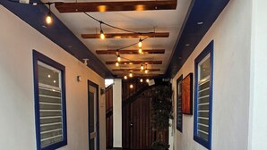 A hallway with dark tiled flooring, wooden beams, and string lights.