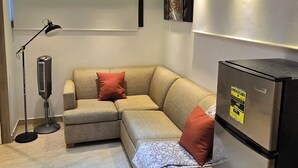 A modern living room with a sectional sofa, a black refrigerator, and a floor lamp.